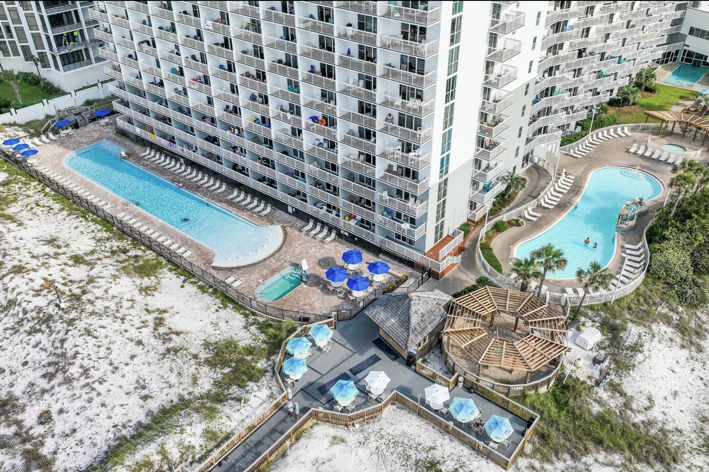 Aerial view of Pelican Beach Resort pools, beachfront deck, dune area and Gulf-side beach route