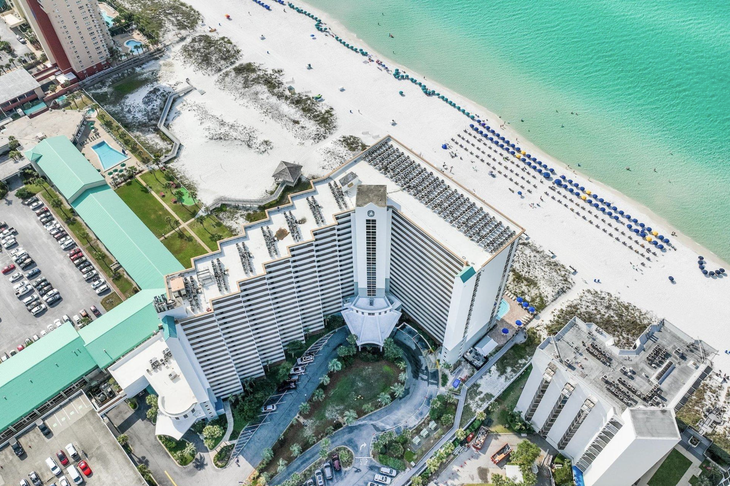 Aerial orientation of Pelican Beach Resort showing US-98, parking, the Gulf-front building, pools, beach boardwalk and shoreline